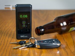 vice is shown with a reading of 0.08 which is the legal limit for a DUI in Michigan. The device is next to car keys and an empty beer bottle on a wooden table.