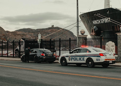 Featured: Police car behind car pulled over for speeding- Can I Get Charged With a Crime for Speeding?